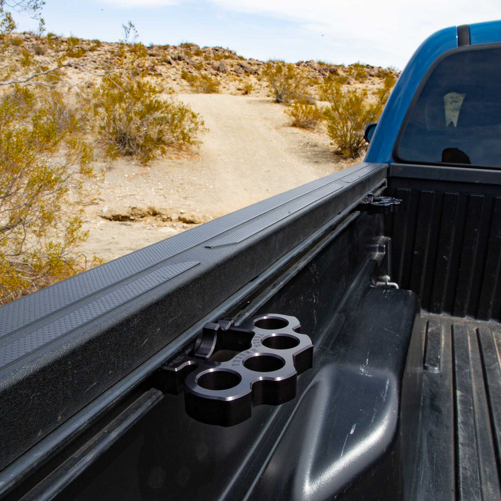 Black Truck Knucks aftermarket truck bed tie-downs in the rail system of Toyota Tacoma off-road in desert