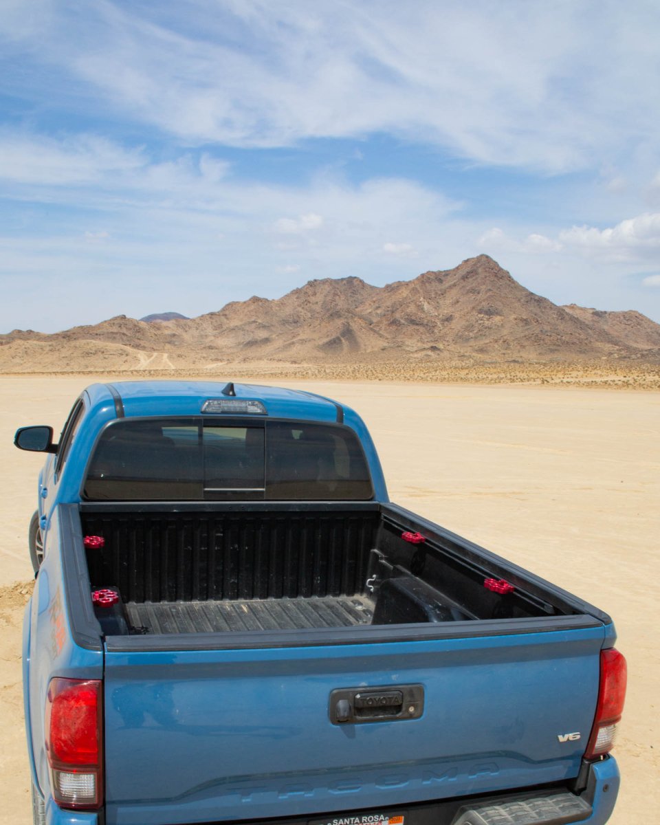 Red Truck knucks in bed of a Toyota Tacoma with desert hill in background